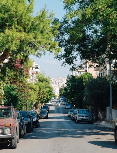 a street with parked cars and trees at Palio Faliro in Athens