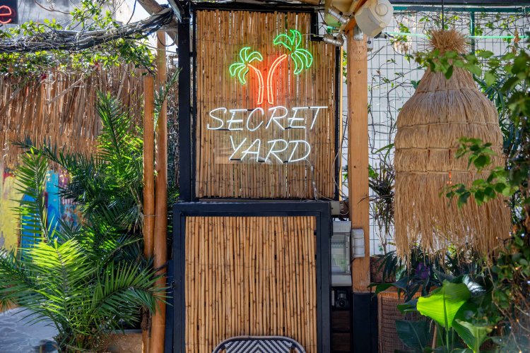 a door with a sign among plants that reads "secret yard"