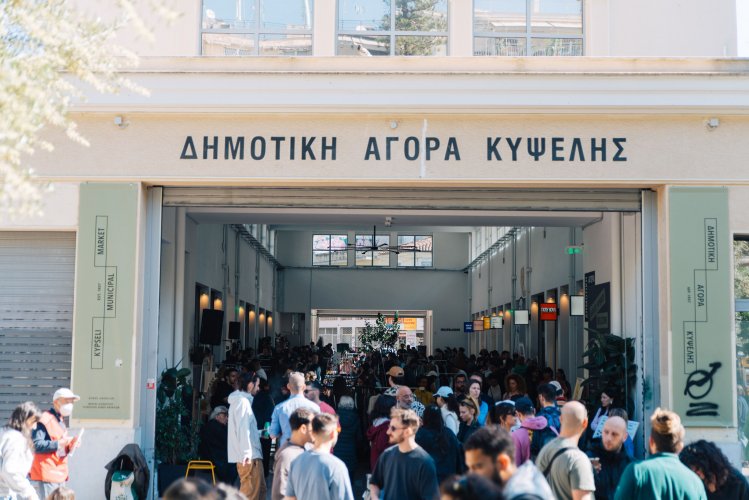 crowd gathered in and outseide an open-air market, a sign that reads "kypseli municipal market"