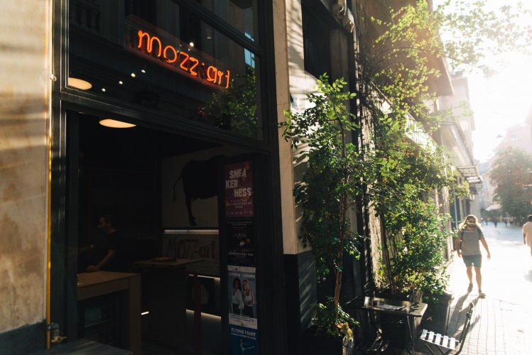 a pizza restaurant with a neon signs that reads "mozzart"