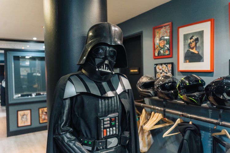 A life-sized Darth Vader costume standing in a tattoo shop. 