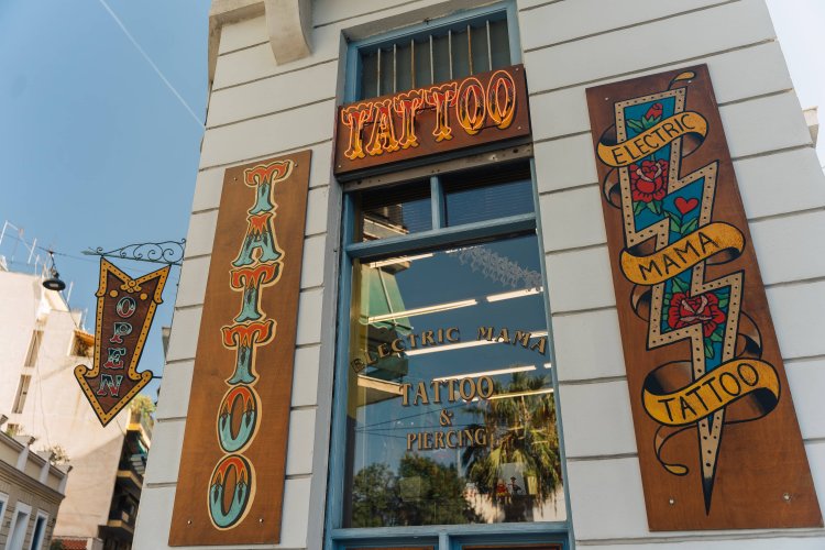 A colorful sign for a tattoo shop. The sign has the words "Tattoo" and "Electric Mama Tattoo" written on it, with a lightning bolt symbol.