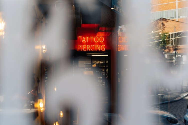 A blurry view of a tattoo and piercing shop with a red sign.