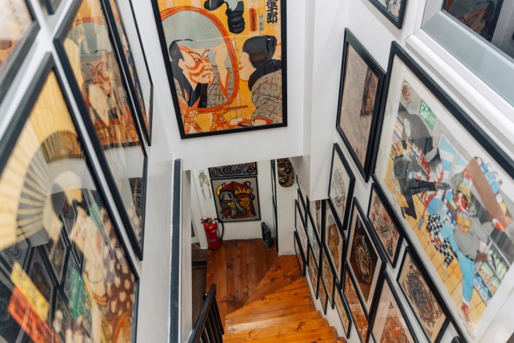 A narrow staircase with framed artwork lining the walls.