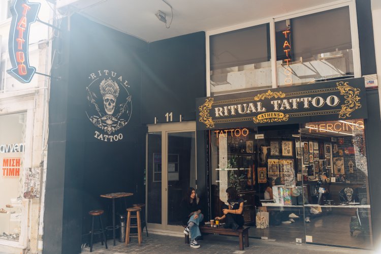 A tattoo shop with a black exterior and a large skull logo, it has a sign that reads "Ritual Tattoo"