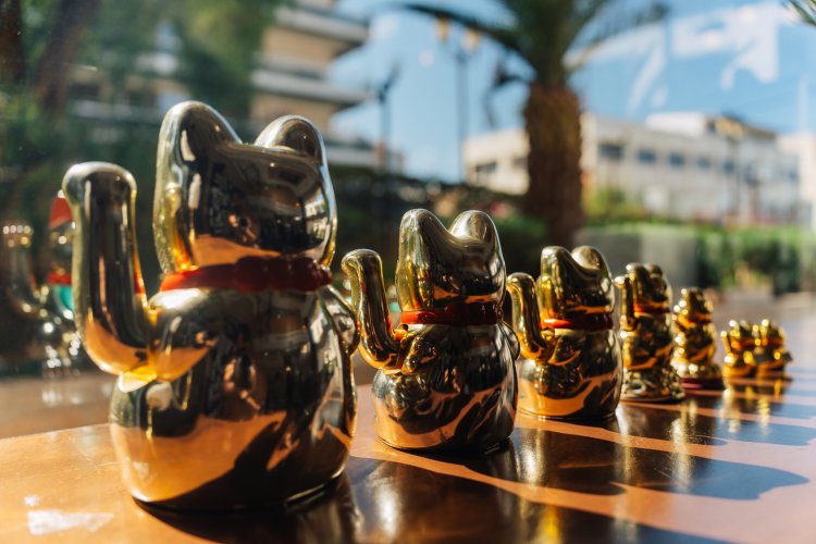 A row of golden Maneki-neko figurines of varying sizes on a wooden surface.