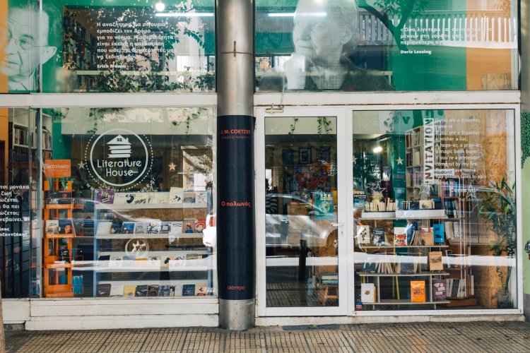 Exterior view of a bookstore with floor-to-ceiling windows showcasing various books and quotes in white text on the glass.