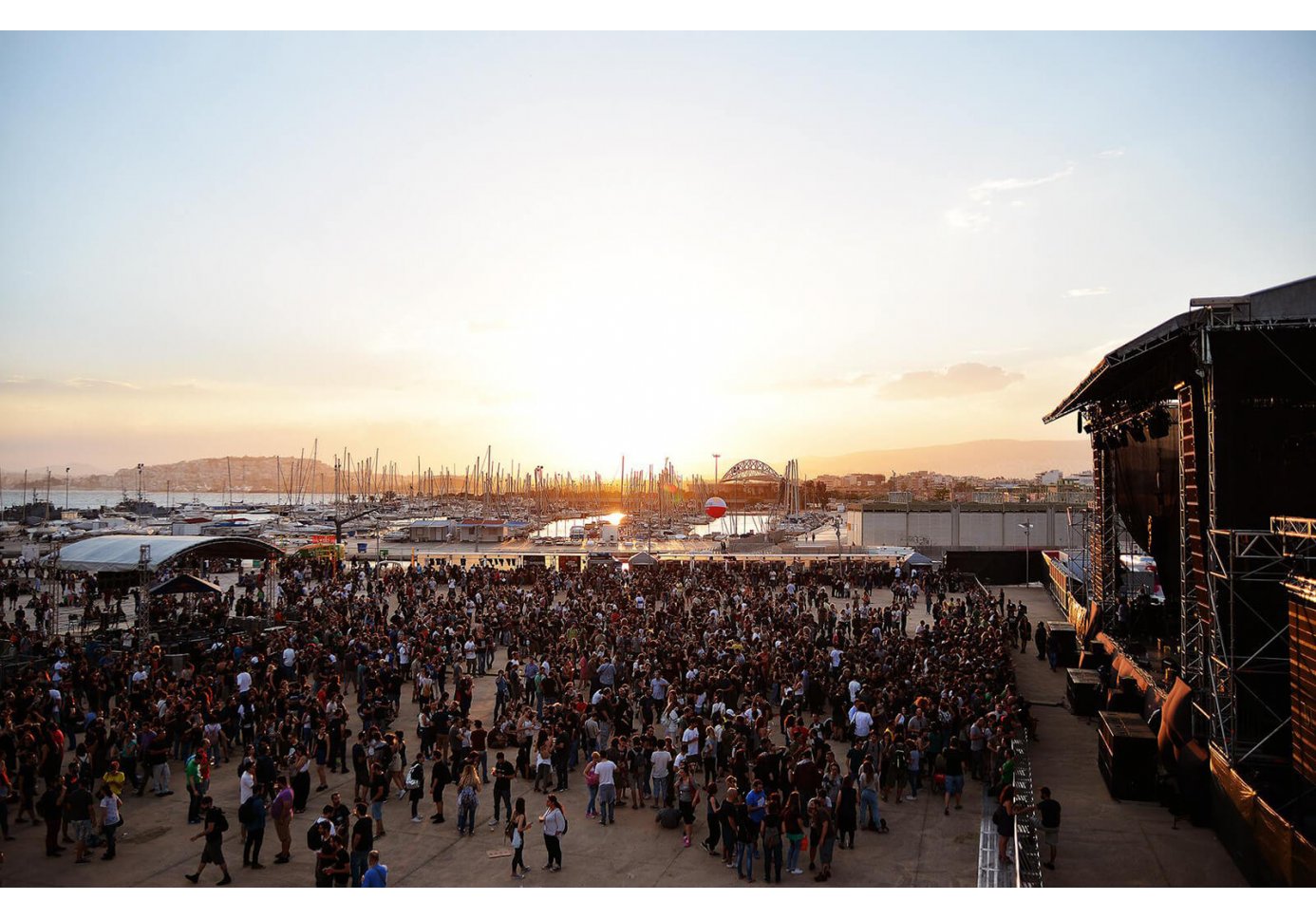 Crowd gathered in front of an open-air stage during sunset