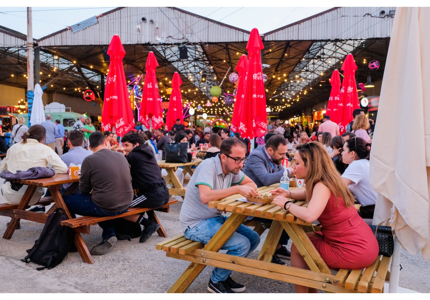 people at a street food festival sitting in benches and tables