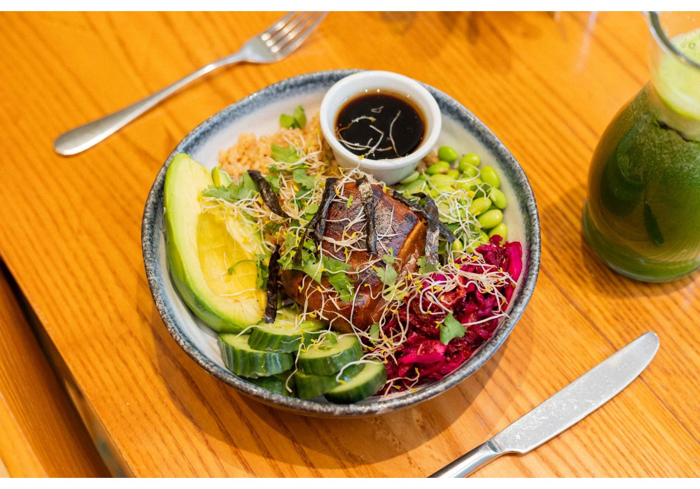 a dish with many colourful vegetables and a green juice.