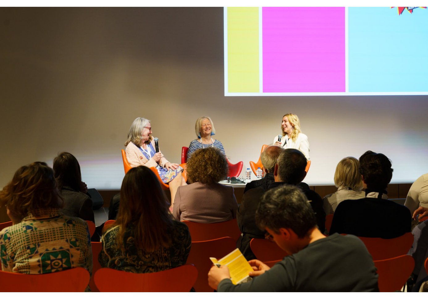 three women on stage talking to a crowd