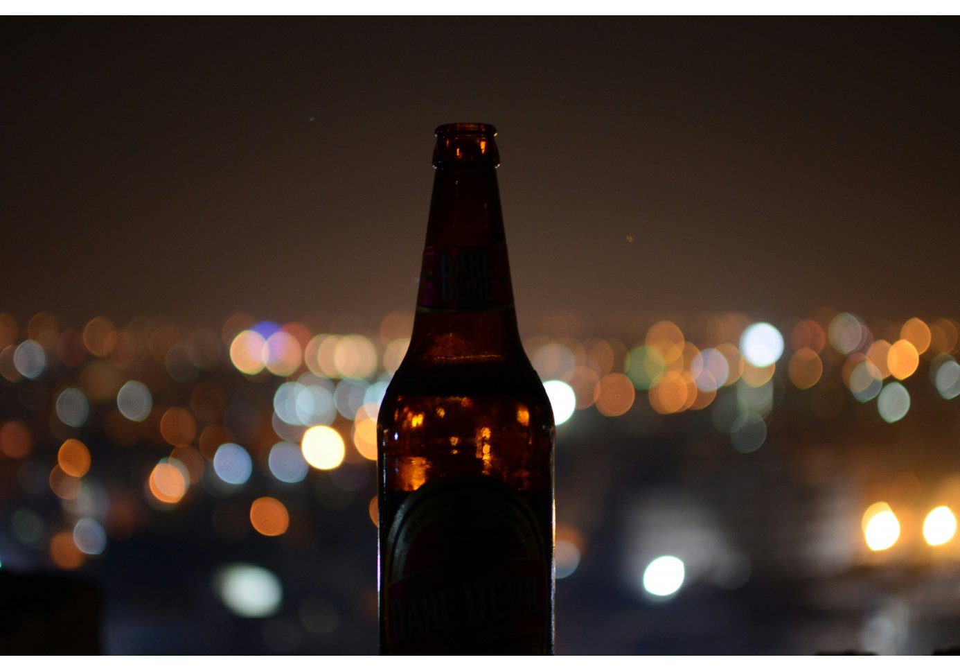 a beer bottle in front of the city lights